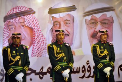 Saudi royal guards stand on duty in front of portraits of King Abdullah bin Abdulaziz (R), Crown Prince Salman bin Abdulaziz (C) and second deputy Prime Minister Muqrin bin Abdulaziz during the traditional Saudi dance known as "Arda" at the Janadriya cu