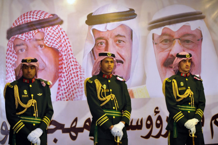 Saudi royal guards stand on duty in front of portraits of King Abdullah bin Abdulaziz (R), Crown Prince Salman bin Abdulaziz (C) and second deputy Prime Minister Muqrin bin Abdulaziz during the traditional Saudi dance known as "Arda" at the Janadriya cu