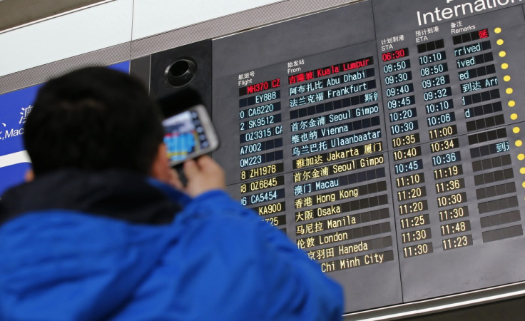 A man takes pictures of a flight information board displaying the Scheduled Time of Arrival (STA) of Malaysia Airlines flight MH370 (top, in red) at the Beijing Capital International Airport in Beijing, March 8, 2014.