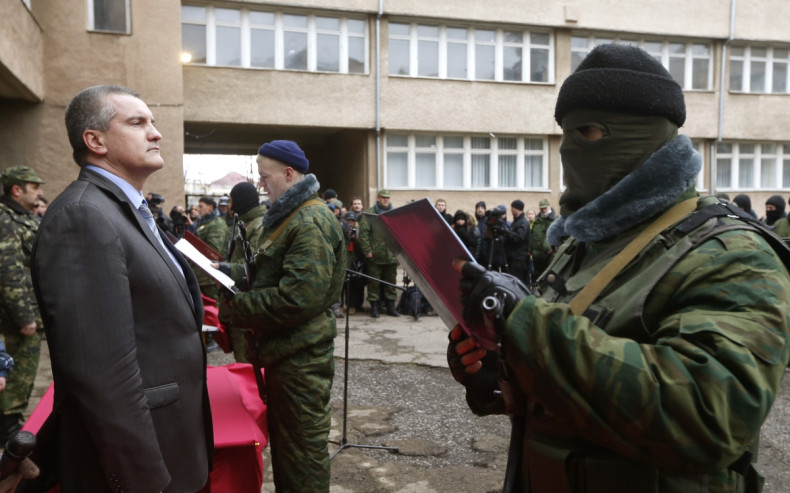 Sergei Aksyonov, Crimea's pro-Russian prime minister, stands as a member of a pro-Russian self defence unit takes an oath to Crimea government in Simferopol