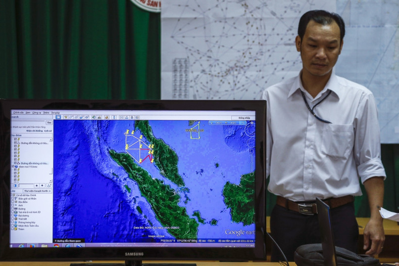 A Vietnamese officer stands next to a TV screen showing a flight route during a news conference about their mission to find missing Malaysia Airlines flight MH370