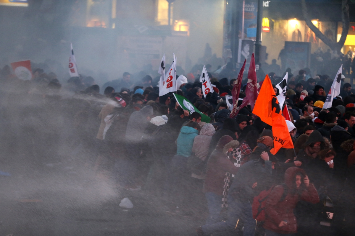 Anti-government protesters run as riot police fires a water cannon during a demonstration in Ankara