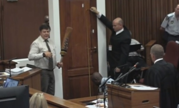 Police officer Lt Col Vermeulen holds the cricket bat next to the toilet door which Oscar Pistorius attack after shooting Reeva Steenkamp