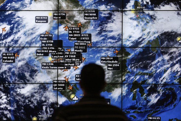 man watches a large screen showing different flights at the departure hall of Kuala Lumpur International Airport