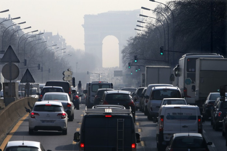 Rush hour traffic on a smoggy avenue leading up to the Arc de Triomphe in western Paris.