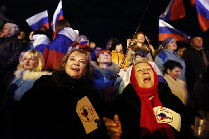 Two women hold flags reading "Crimea is with Russia" as people wait for the announcement of preliminary results of today's referendum on Lenin Square in the Crimean capital of Simferopol