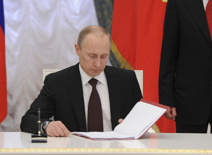 Russian President Vladimir Putin prepares to sign a law on ratification of a treaty making Crimea part of Russia