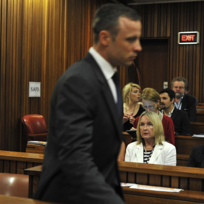 June Steenkamp (in white) watches Oscar Pistorius walk to the dock at his trial for killing Reeva Steenkamp