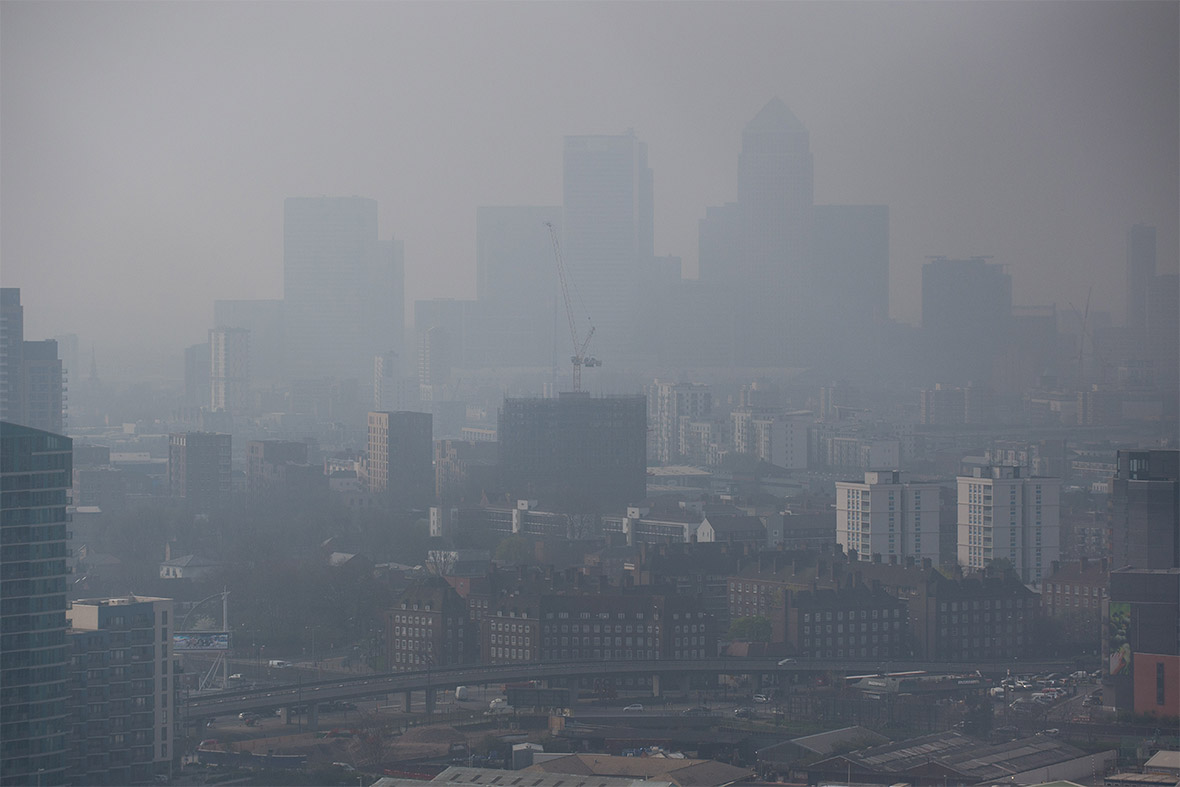 The Canary Wharf financial district is dimly seen through the smog blanketing London