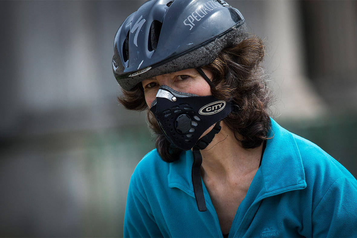A woman wearing an anti-pollution mask rides a bicycle at Hyde Park Corner