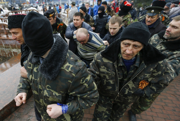 Pro-Russian protesters escort a man detained yesterday, who they said provoked them by trying to sell a pistol, near the seized office of the SBU state security service in Luhansk, in eastern Ukraine