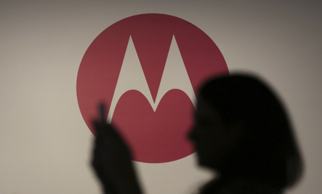 A woman takes a picture in front of a Motorola logo A woman takes a picture in front of a Motorola logo