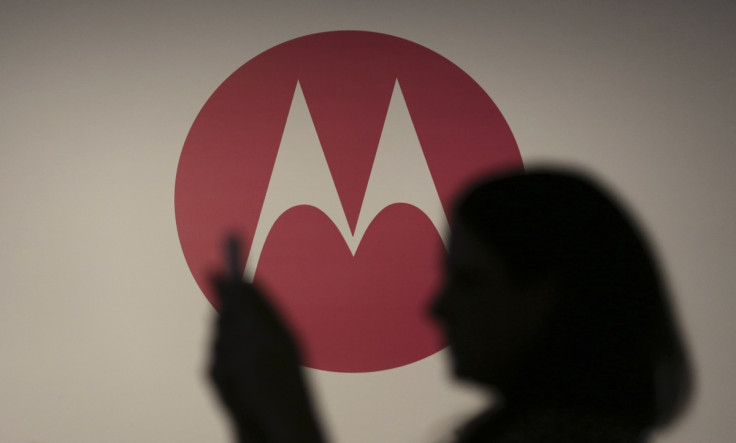 A woman takes a picture in front of a Motorola logo