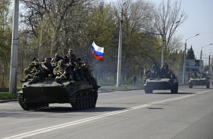 Armed men, wearing black and orange ribbons of St. George - a symbol widely associated with pro-Russian protests in Ukraine, drive an airborne combat vehicle (L) with a Russian flag seen on the top, outside Kramatorsk