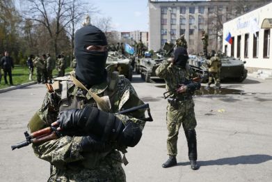 Armed men, wearing black and orange ribbons of St. George - a symbol widely associated with pro-Russian protests in Ukraine, stand guard hear armoured personnel carriers in Slaviansk