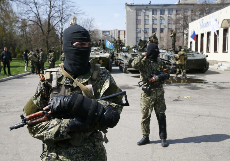 Armed men, wearing black and orange ribbons of St. George - a symbol widely associated with pro-Russian protests in Ukraine, stand guard hear armoured personnel carriers in Slaviansk