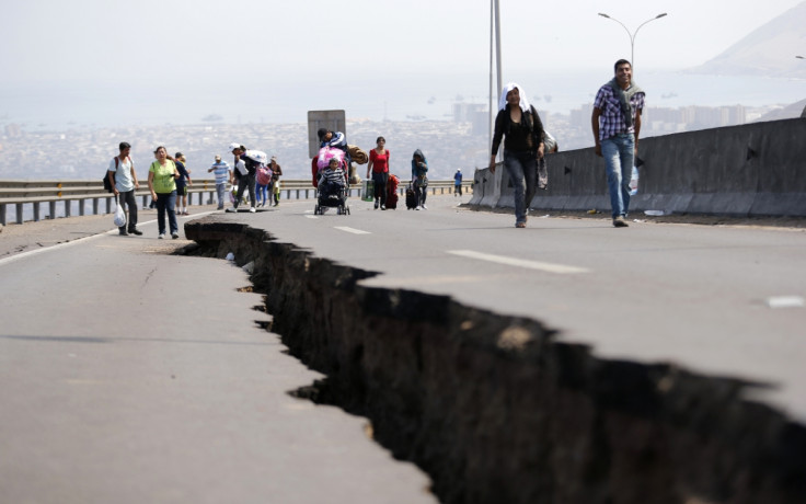 People walk next to a crack along a damaged road leading to Alto Hospicio commune, after a series of aftershocks, in the northern port of Iquique April 3