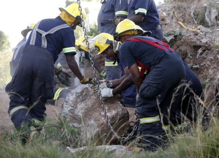 Rescue officials move a rock removed from an abandoned gold shaft as they work to rescue trapped suspected illegal miners in Benoni, east of Johannesburg