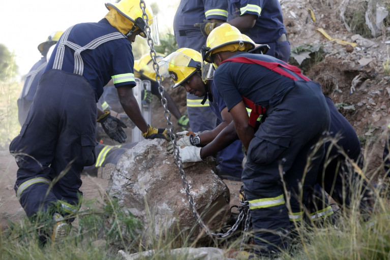 Rescue officials move a rock removed from an abandoned gold shaft as they work to rescue trapped suspected illegal miners in Benoni, east of Johannesburg