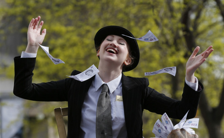 A demonstrator dressed as a banker throws away imitation bank notes during a protest outside the Barclays AGM in central London April 24, 2014.