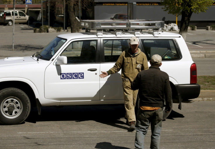 Municipal workers take a photo at an Organization for Security and Cooperation in Europe (OSCE) car near the seized office of the SBU state security service in Luhansk, eastern Ukraine