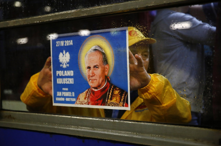 A Polish pilgrim holds up a poster as he travels to the Vatican to witness the canonisations of Pope John XXIII and Pope John Paul II