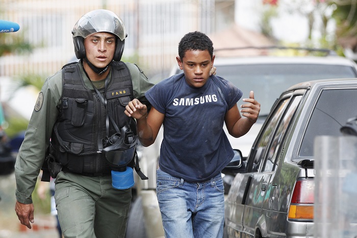 A young protester is detained by police during protests against education reforms in Venezuela. A young protester is detained by police during protests against education reforms in Venezuela.