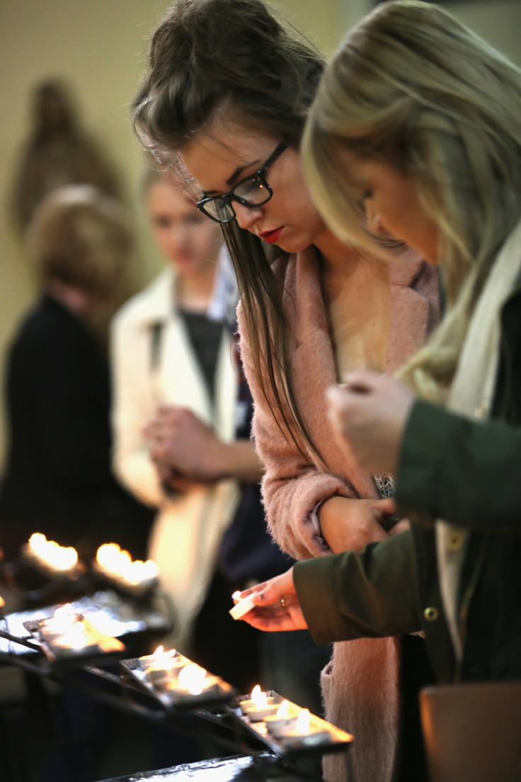 Mourners light candles at a mass for Anne Maguire at Corpus Christi Church, after the teacher was stabbed to death during class in Leeds