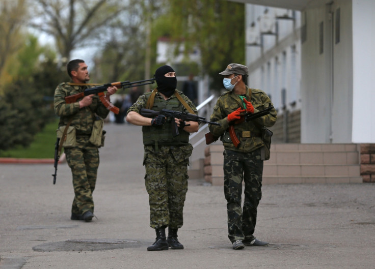 Pro-Russian armed men walk near the local police headquarters in Luhansk, eastern Ukraine