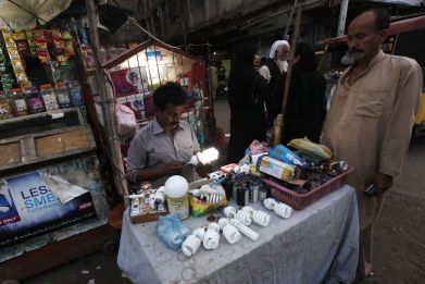 Man checks lightbulb in Karachi slum