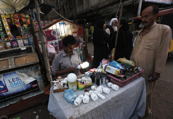 Man checks lightbulb in Karachi slum