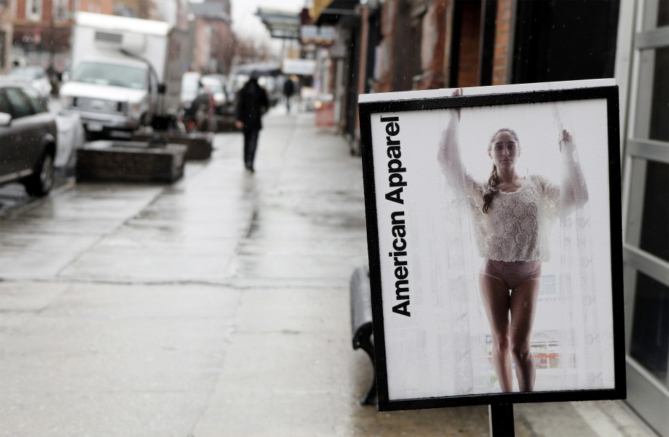 Pedestrians walk past an American Apparel sign outside one of their stores in New York