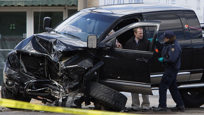 Royal Canadian Mounted Police officers inspect a smashed up truck involved in the shooting incident in St Paul, Alberta.