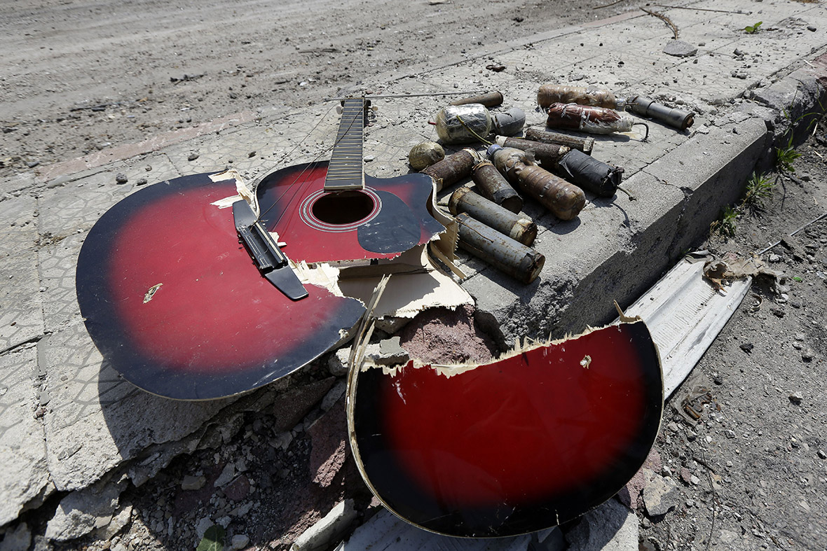 A broken guitar lies  on the street  next to handmade grenades the Old City of Homs