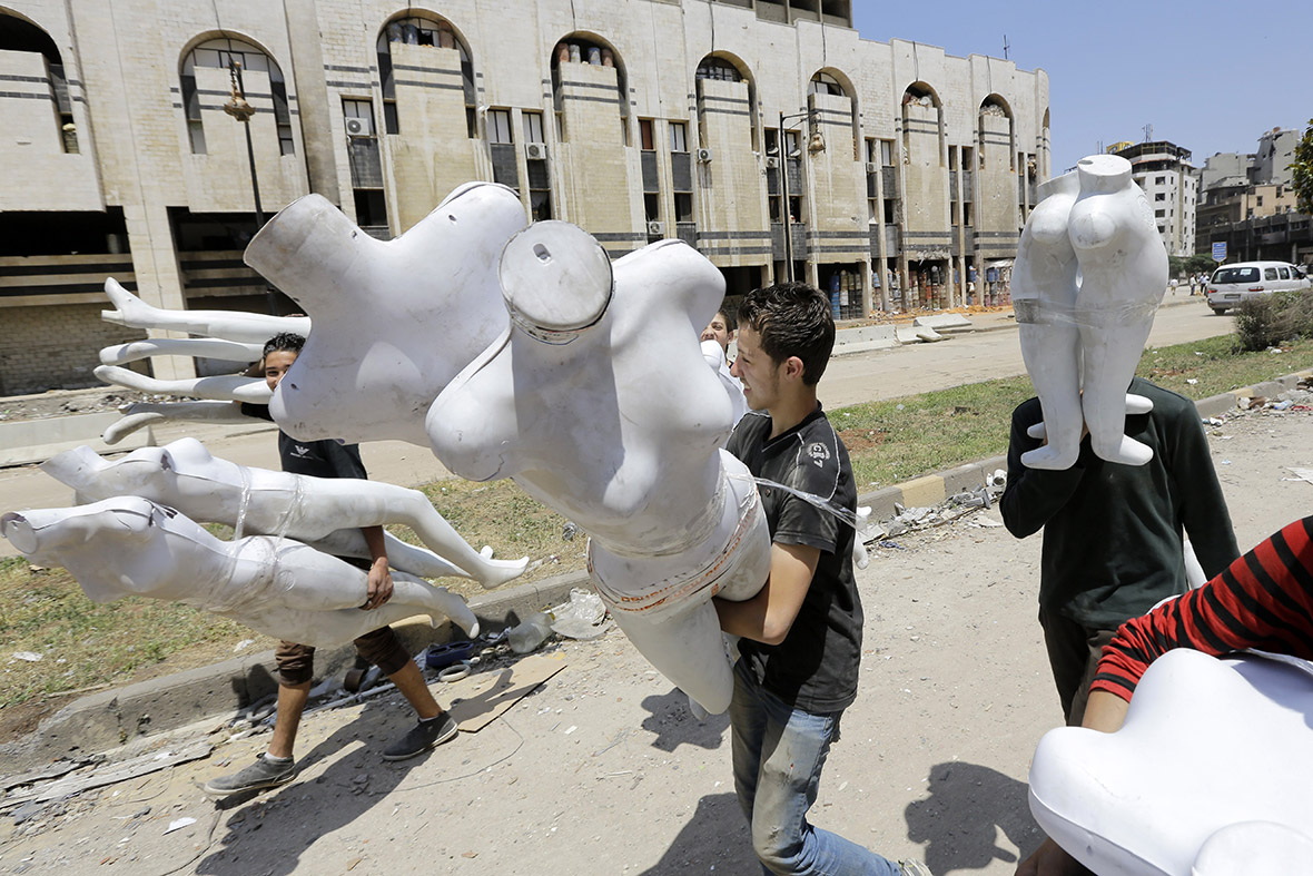 Syrian children carry shop mannequins in a destroyed neighbourhood of the Old City of Homs