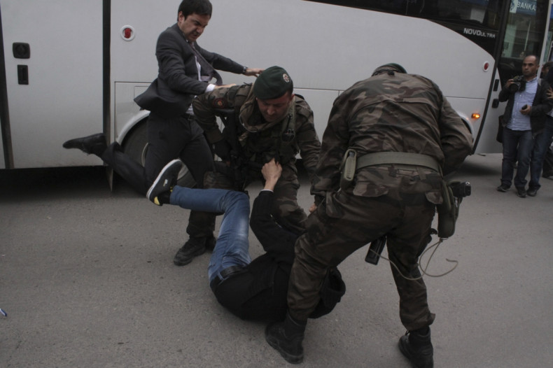 A protester is kicked by Yusuf Yerkel (L), advisor to Turkey's Prime Minister Tayyip Erdogan, as Special Forces police officers detain him during a protest against Erdogan's visit to Soma