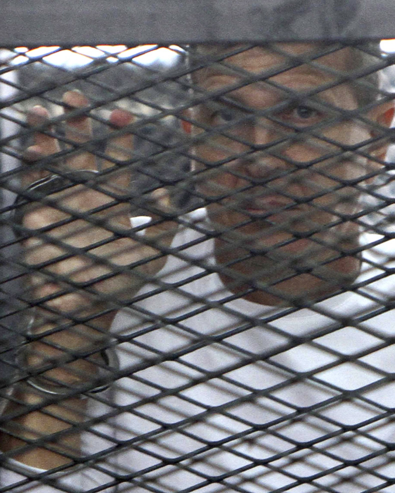 Al Jazeera journalist Peter Greste of Australia stands in a metal cage during his trial in a court in Cairo