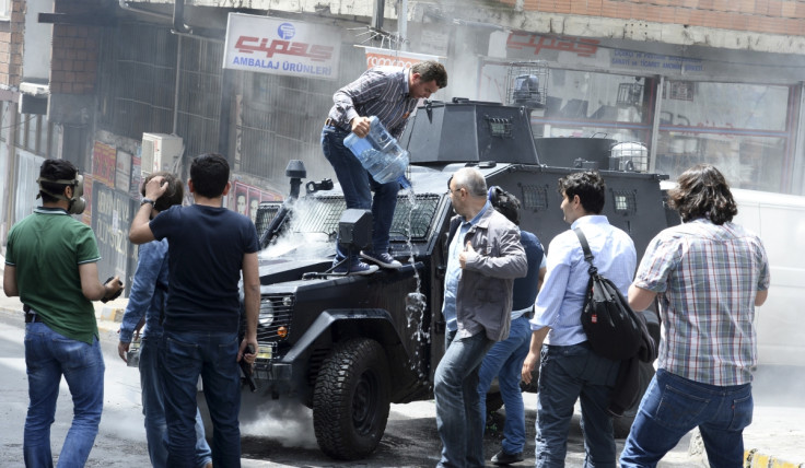 A man pours water on an armoured police vehicle after it was set on fire by fire bombs during clashes between protesters and riot police in Istanbul
