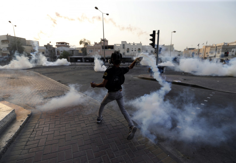 An anti-government protester throws back a tear-gas canister that was fired by the police as they clash during a funeral procession