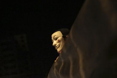 A demonstrator of the group called Black Bloc wears an anonymous mask as he holds a banner during a protest  in Sao Paulo