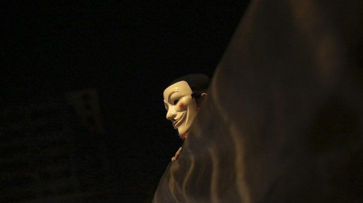 A demonstrator of the group called Black Bloc wears an anonymous mask as he holds a banner during a protest  in Sao Paulo