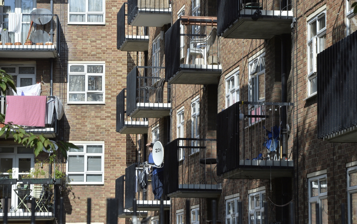 A man stands on a balcony in a residential high rise block of flats in Notting Hill in central London