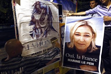 French far-right National Front activists prepare to cover up a poster advertising an upcoming concert by U.S. singer Madonna with a poster of their leader Marine Le Pen (R) in Nice August 18, 2012