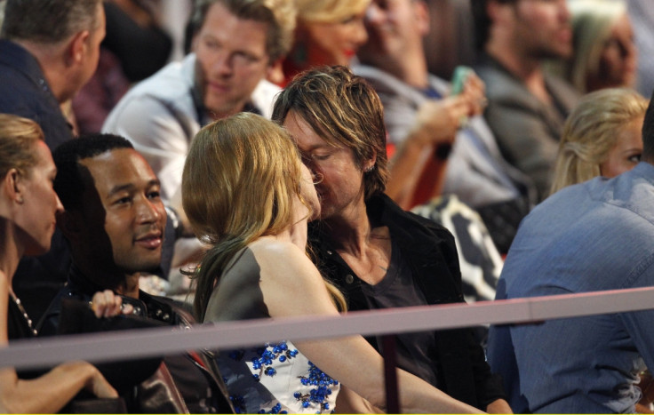 Nicole Kidman and husband Keith Urban kiss in the audience as musician John Legend (L) sits nearby during the 2014 CMT Music Awards in Nashville, Tennessee.