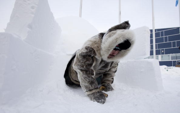 Inuit hunter Pitseolak Alainga crawls out of an igloo in Iqaluit, Canada