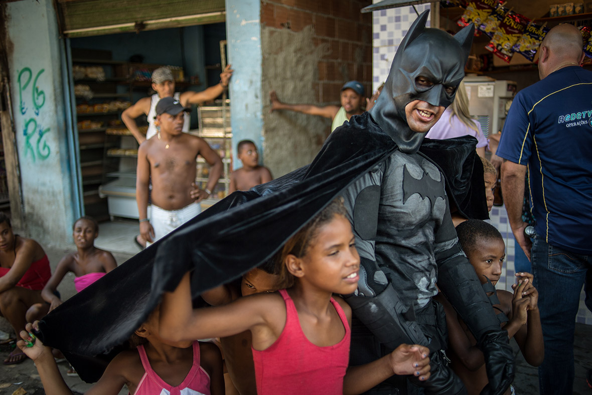 Children throng around Eron Morais de Melo, disguised as Batman, at the Favela do Metro slum area near the Maracana stadium in Rio on January 9, 2014. Families living in this shantytown were refusing to have their homes demolished as part of a project to 