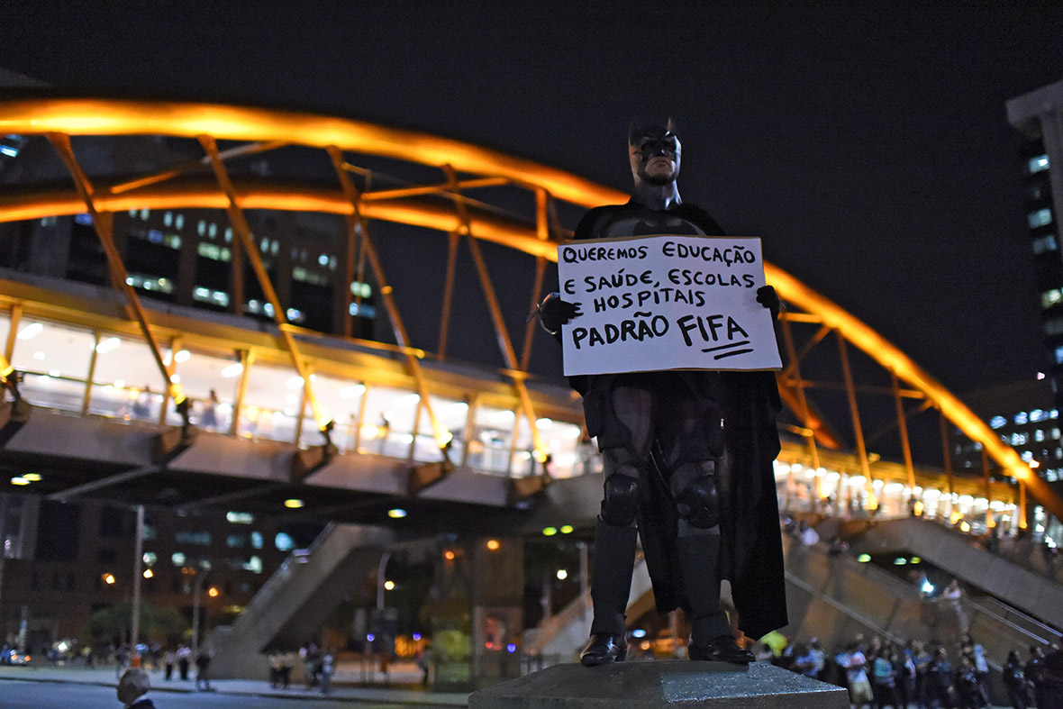The Dark Knight holds a placard reading We want education, health, schools and hospitals at Fifa standards on May 15, 2014