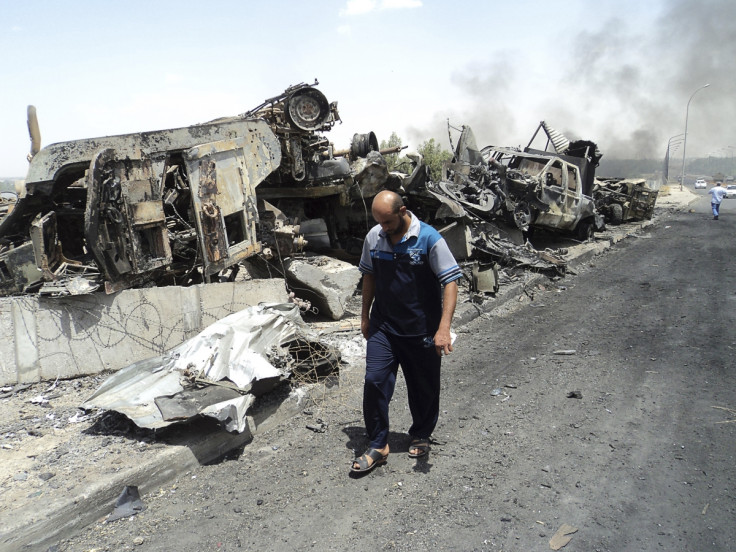 A man walks past near remains of burnt vehicles belonging to Iraqi security forces in the northern Iraq city of Mosul