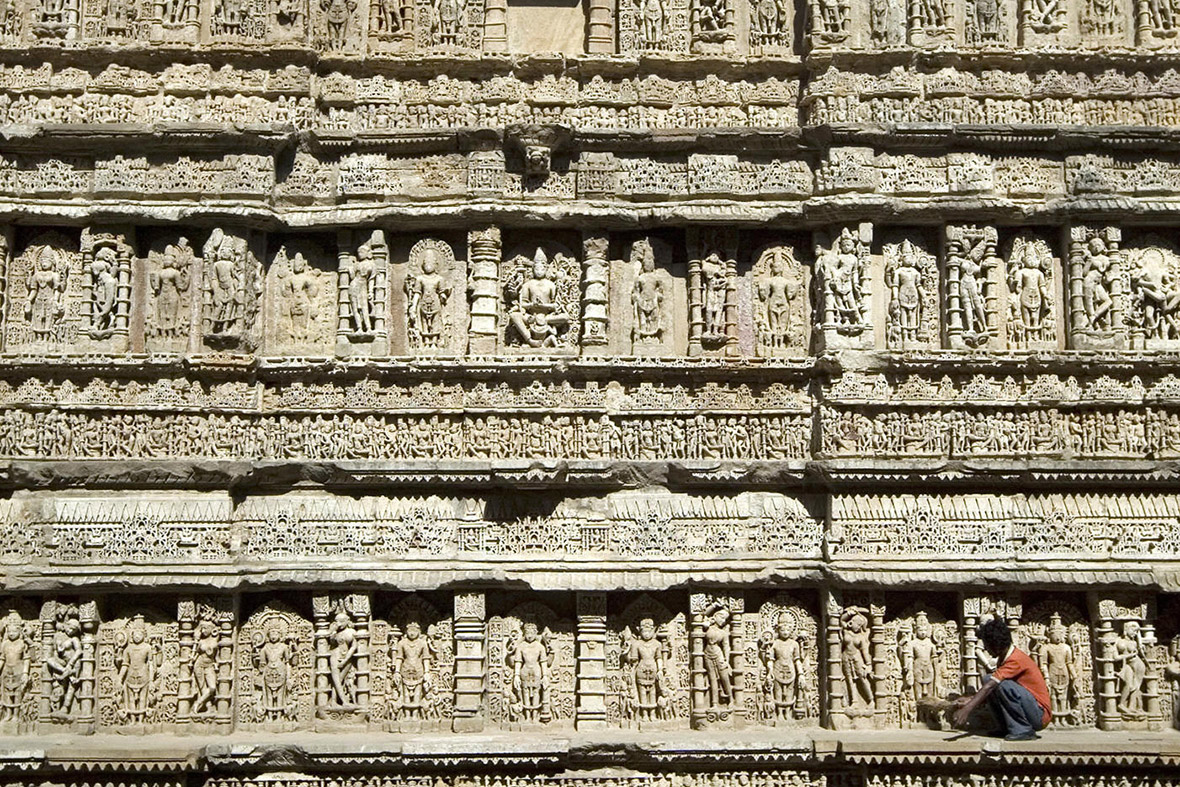 worker sweeps the carved walls of The Ran Ki Vav Queens Stepwell