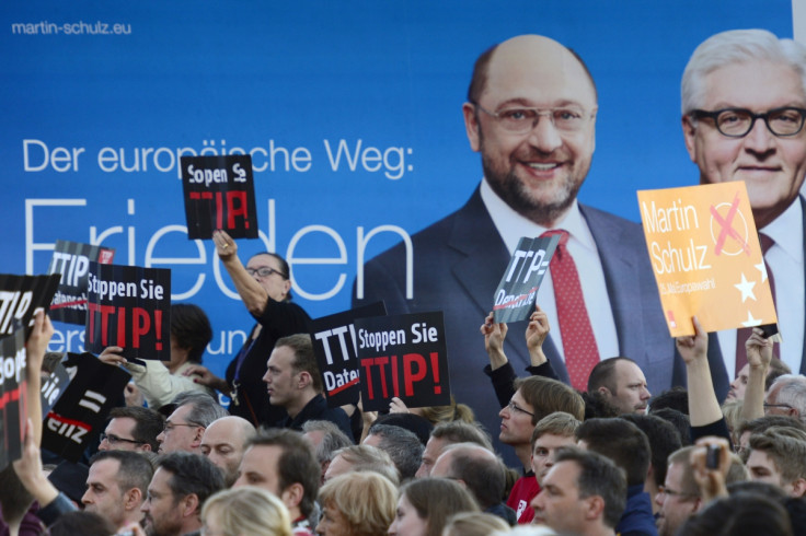Protesters demonstrating against the Transatlantic Trade and Investment Partnership TTIP hold up signs in front of a placard picturing German Foreign Minister Frank-Walter Steinmeier.